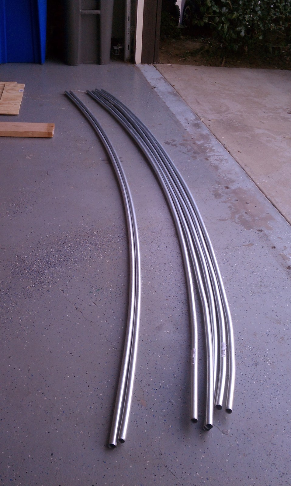 Four bent conduit ribs laid side by side on the garage floor.