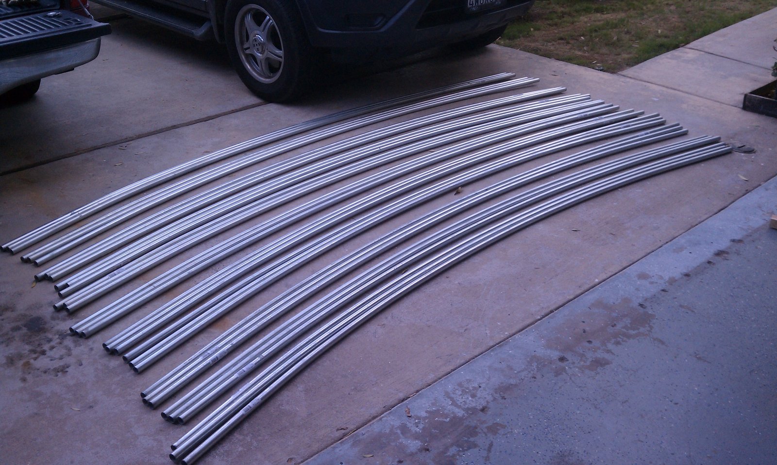 The full set of bent conduit ribs stacked in an overlapping fan on the driveway.