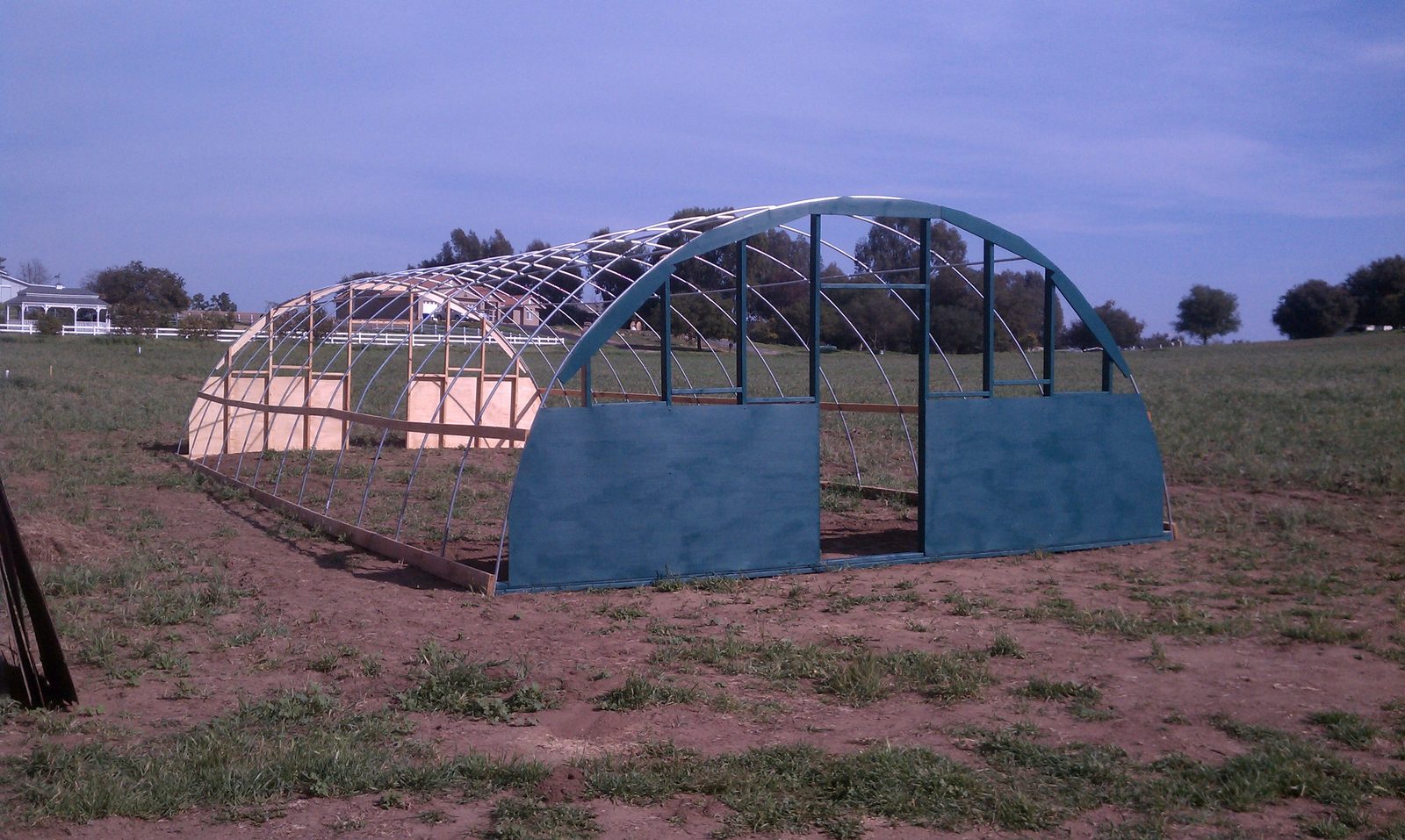 The hoop house fully covered in white greenhouse plastic.