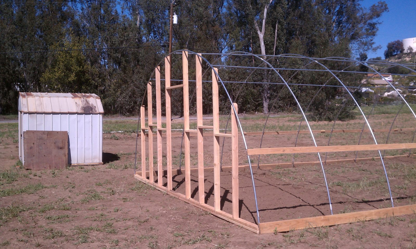 Close view of the timber studs framing the end wall of the hoop house.
