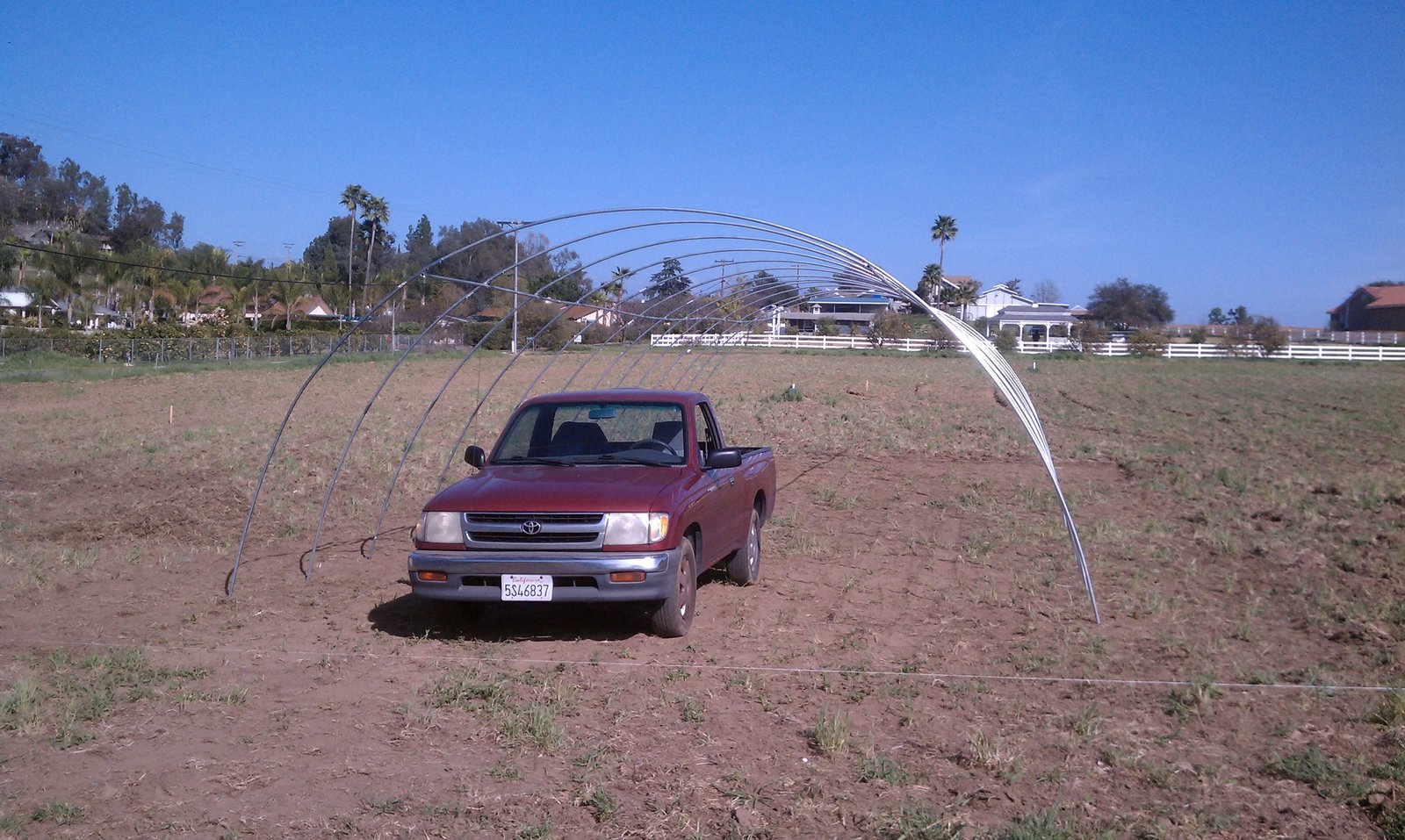 Bent ribs arching over the pickup truck parked inside the building footprint.