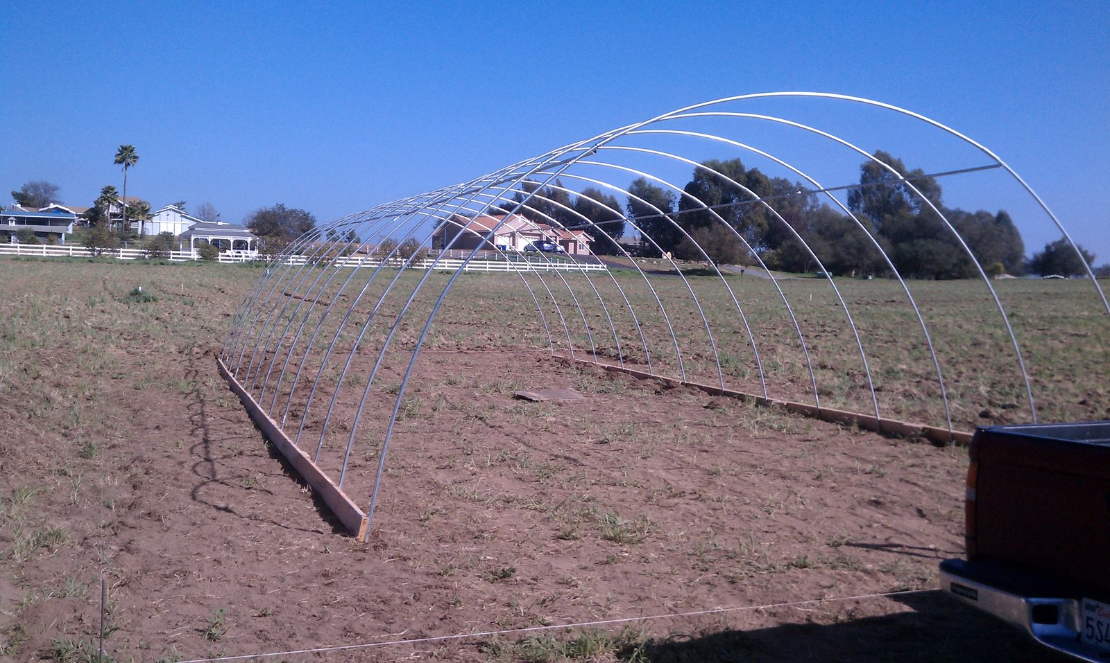 The first bent ribs standing upright in the field against a clear sky.
