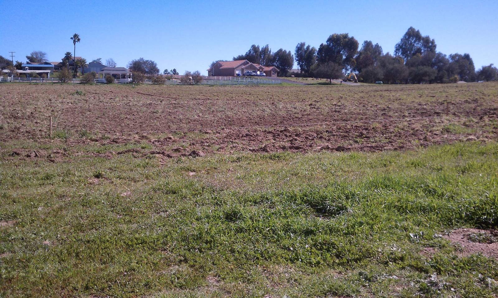 The parcel with its soil freshly turned over, green grass in the foreground and houses beyond.