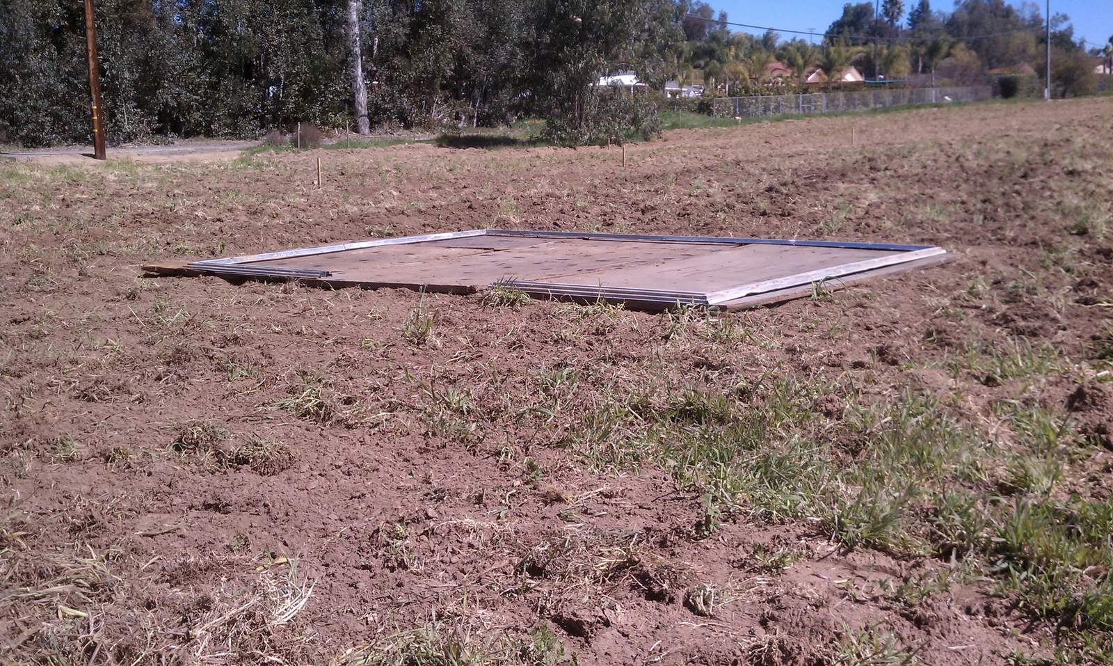 A timber floor platform lying flat on cleared ground at the field.