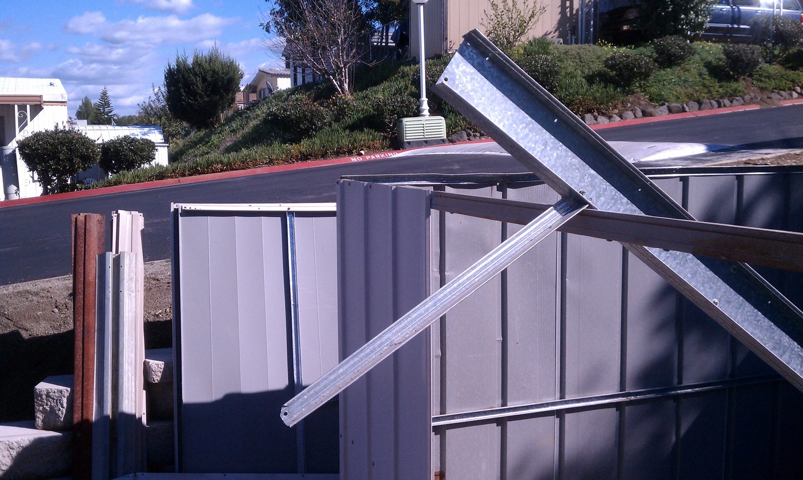 Shed wall panels and galvanized rails leaning in a stack as the shed is taken apart.