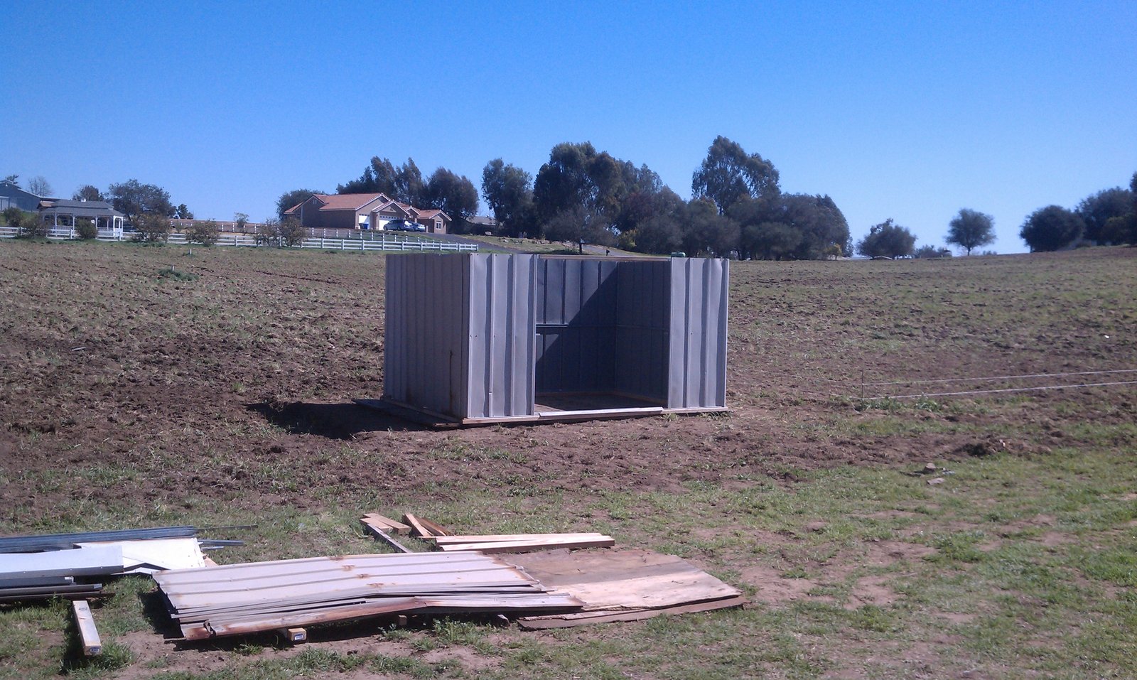 The shed part rebuilt on the field, walls standing and panels laid out in the grass.