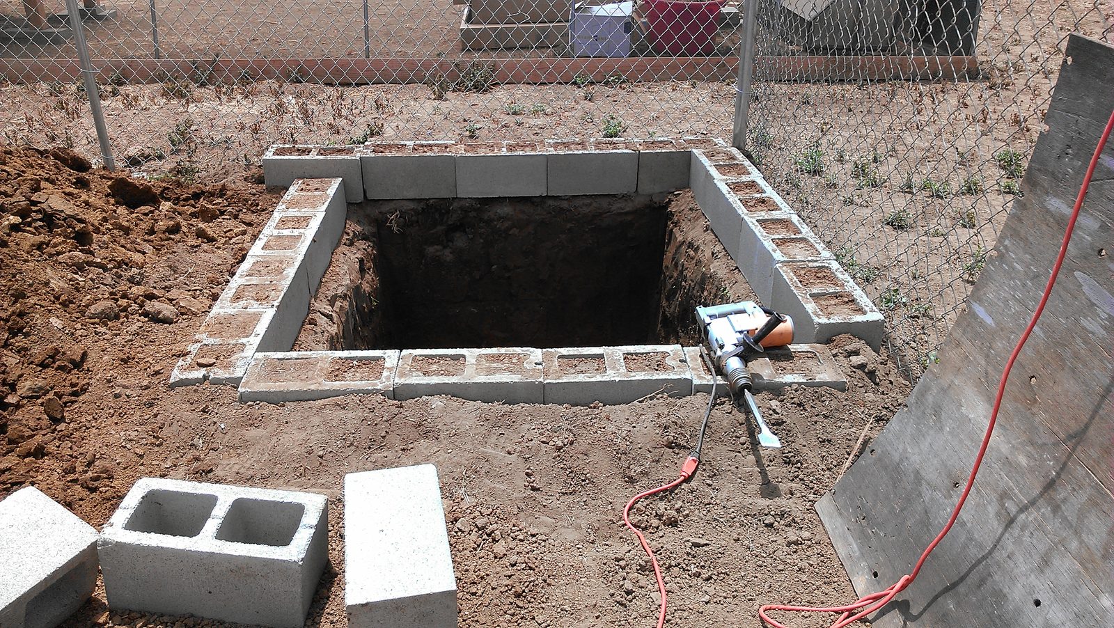 The sump pit lined with concrete blocks forming a retaining wall around it.